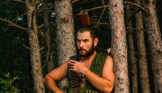 man wearing a khaki top waiting by the tree