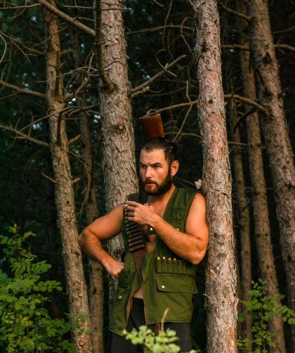 man wearing a khaki top waiting by the tree