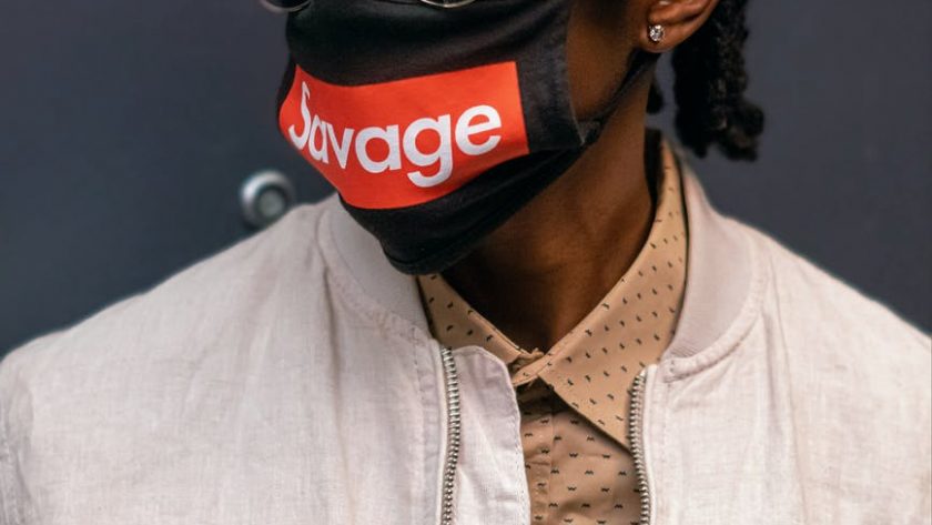 man wearing a beige jacket and facemask posing